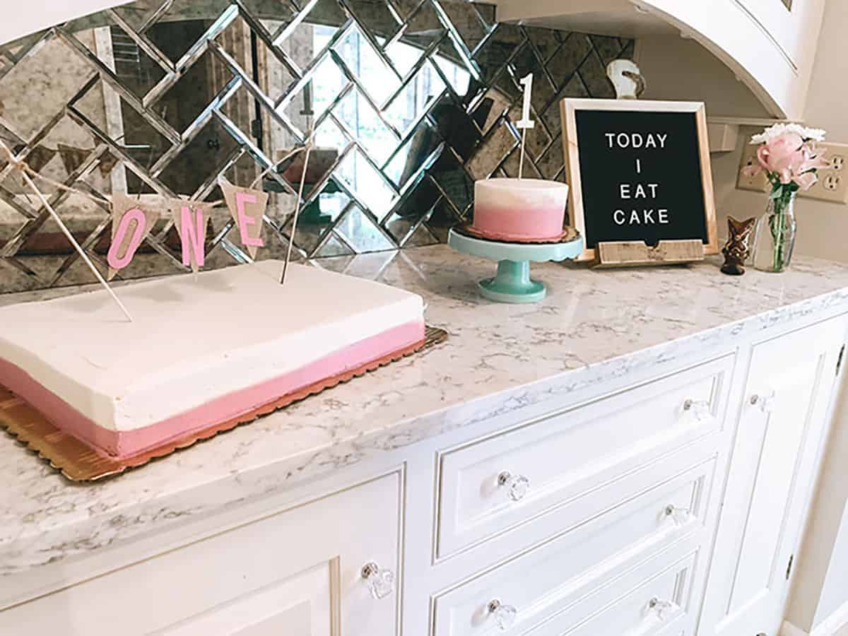 pink and white birthday cakes on counter with sign that says "today I eat cake"