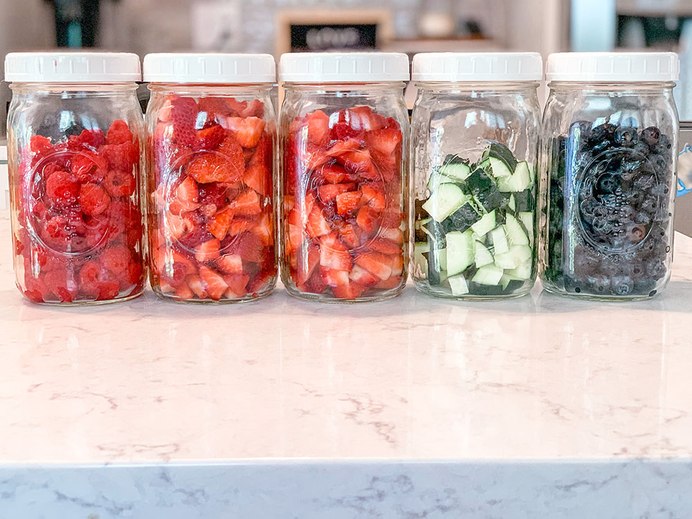 Glass mason jars full of cut up fruit and veggies for food prep