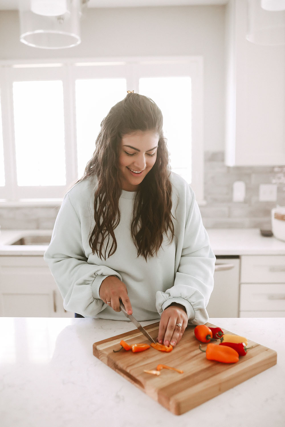 Chopping veggies for food prep in a white kitchen on butcher block cutting board