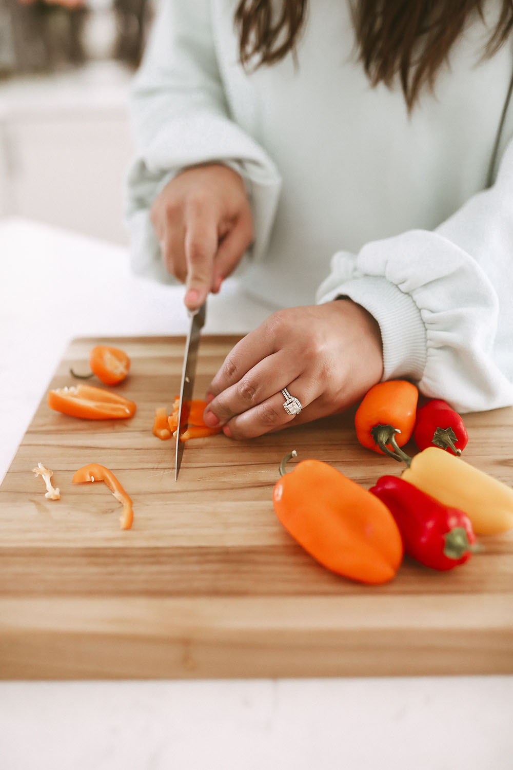 Chopping veggies for food prep in a white kitchen on butcher block cutting board