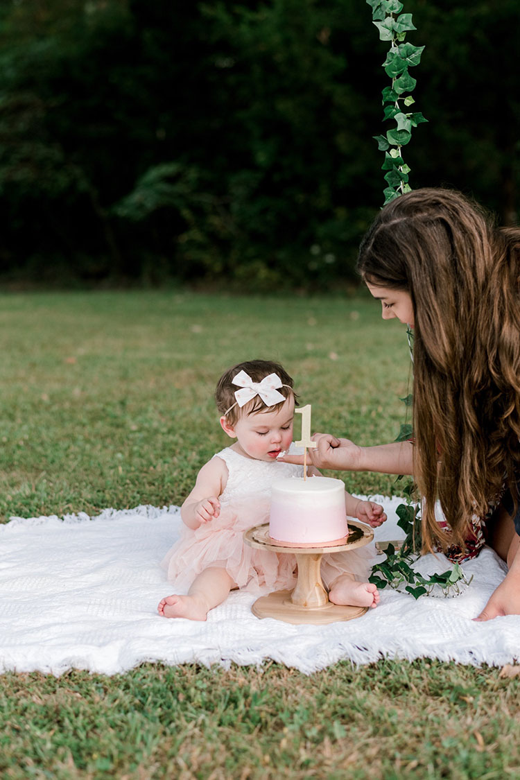 one year old photoshoot with little girl wearing pink tulle dress eating cake