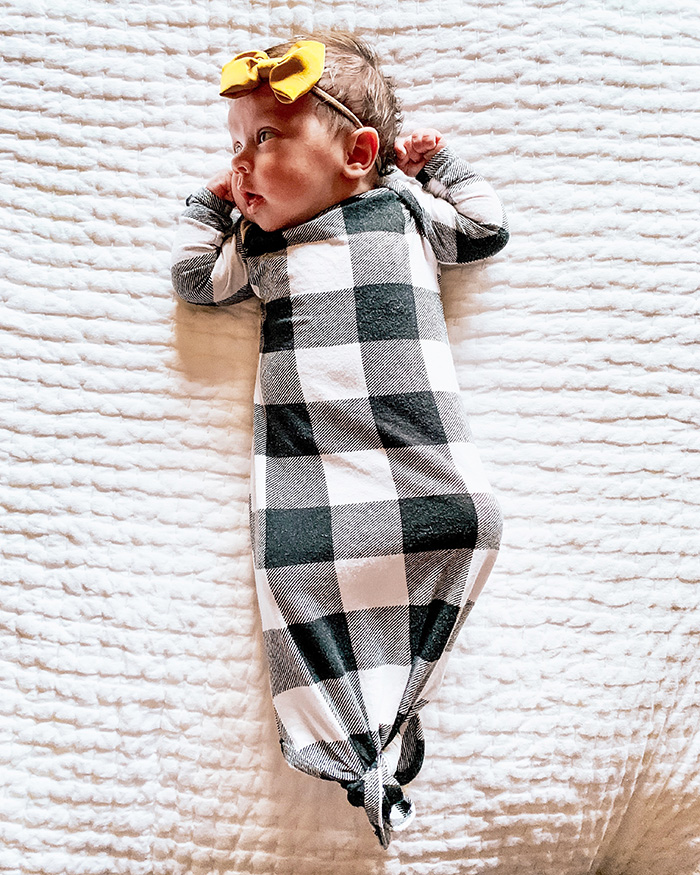 one month old girl wearing black and white gown and yellow bow