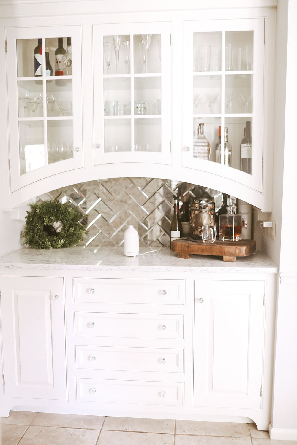 Wetbar showing wooden stand with decanter full of bourbon, basket holding corks, bottle opener and clear rocks glasses