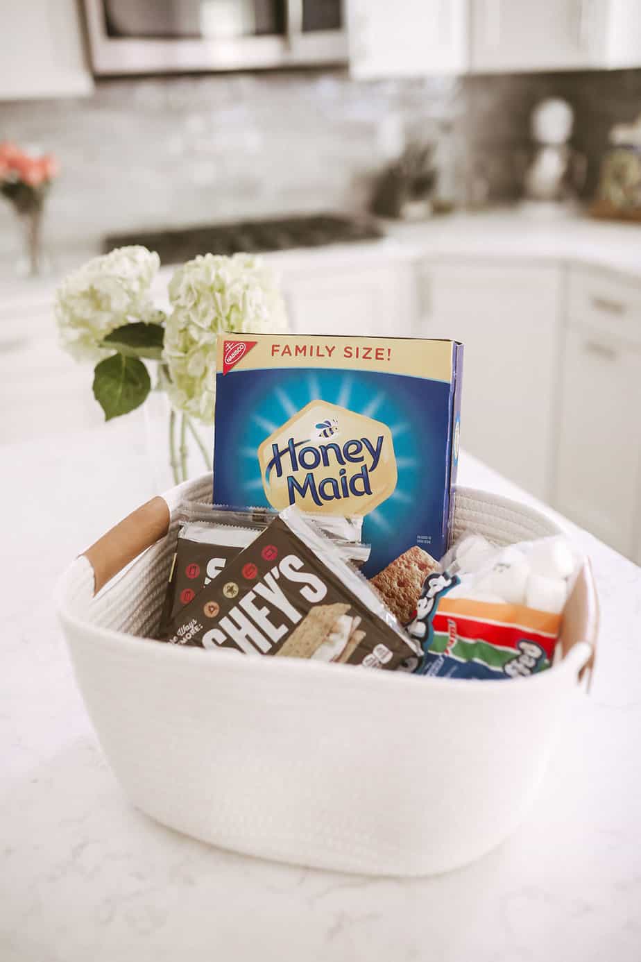 white rope basket full of smores ingredients sitting on a white kitchen island