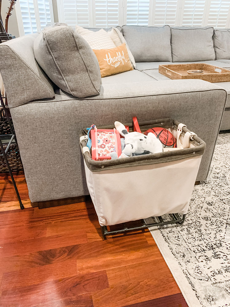 Basket of toys sitting next to a grey sectional couch