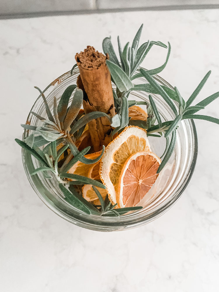 Jar full of stovetop potpourri with dried citrus, spices, rosemary, and more