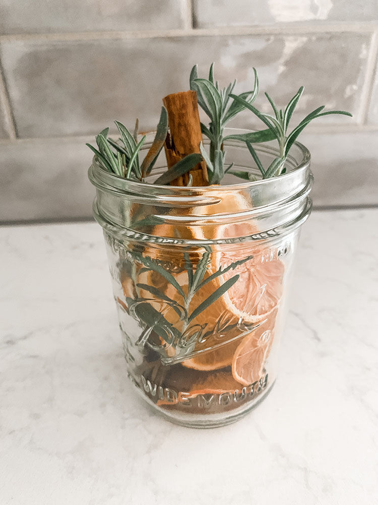 Jar full of stovetop potpourri with dried citrus, spices, rosemary, and more