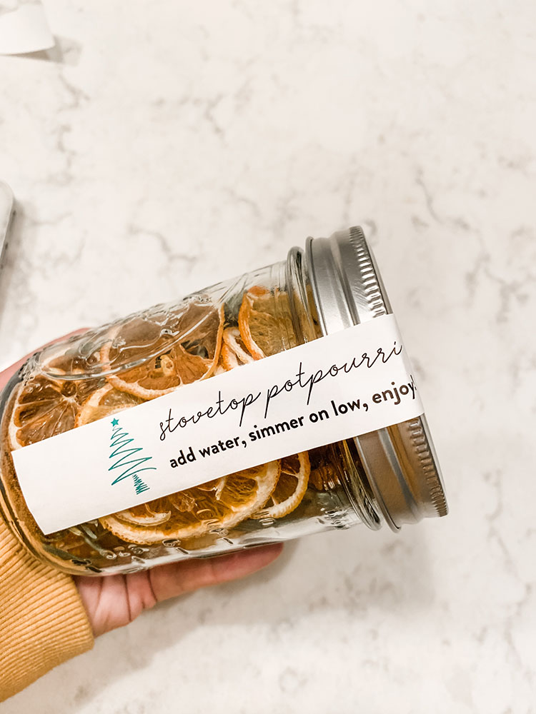 Jar full of stovetop potpourri with dried citrus, spices, rosemary, and more