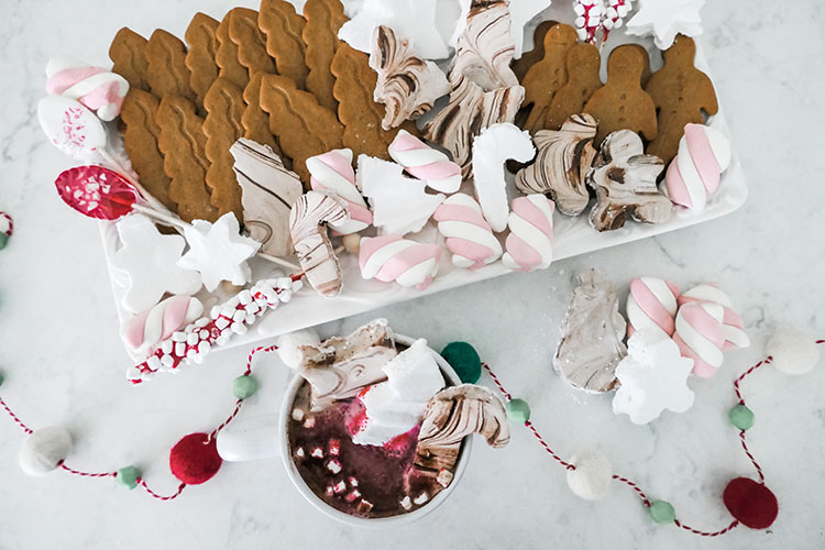 Homemade marshmallows in shapes of trees, stars, candy canes with tray of hot cocoa bar ingredients