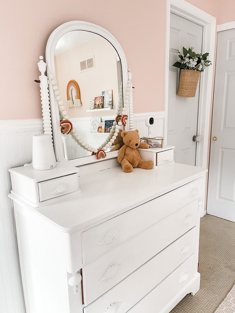 Little girl's pink and white bedroom showing white dresser with bear on top.