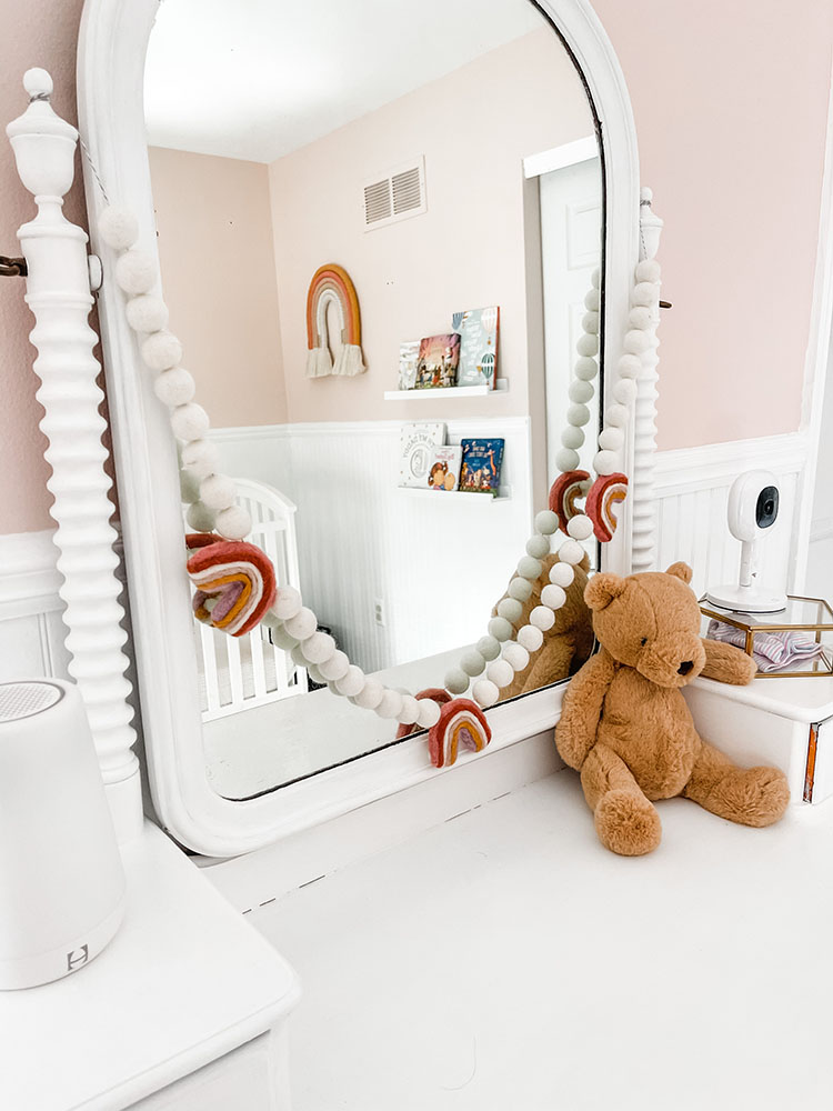 Little girl's pink and white bedroom showing white dresser with bear on top and large mirror