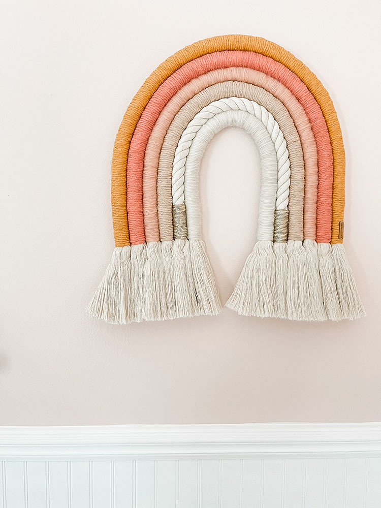 Little girl's pink and white bedroom with macrame rainbow art on the wall