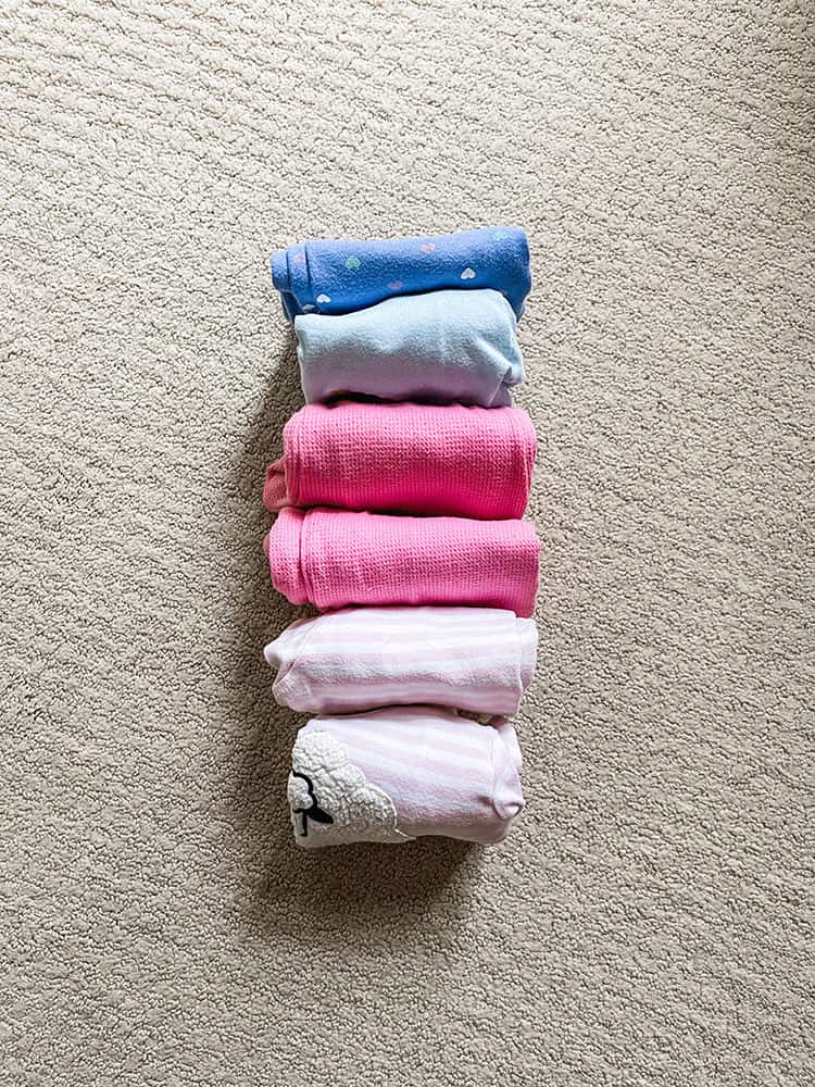 Three sets of toddler girl pajamas file folded and standing up on their ends in color order