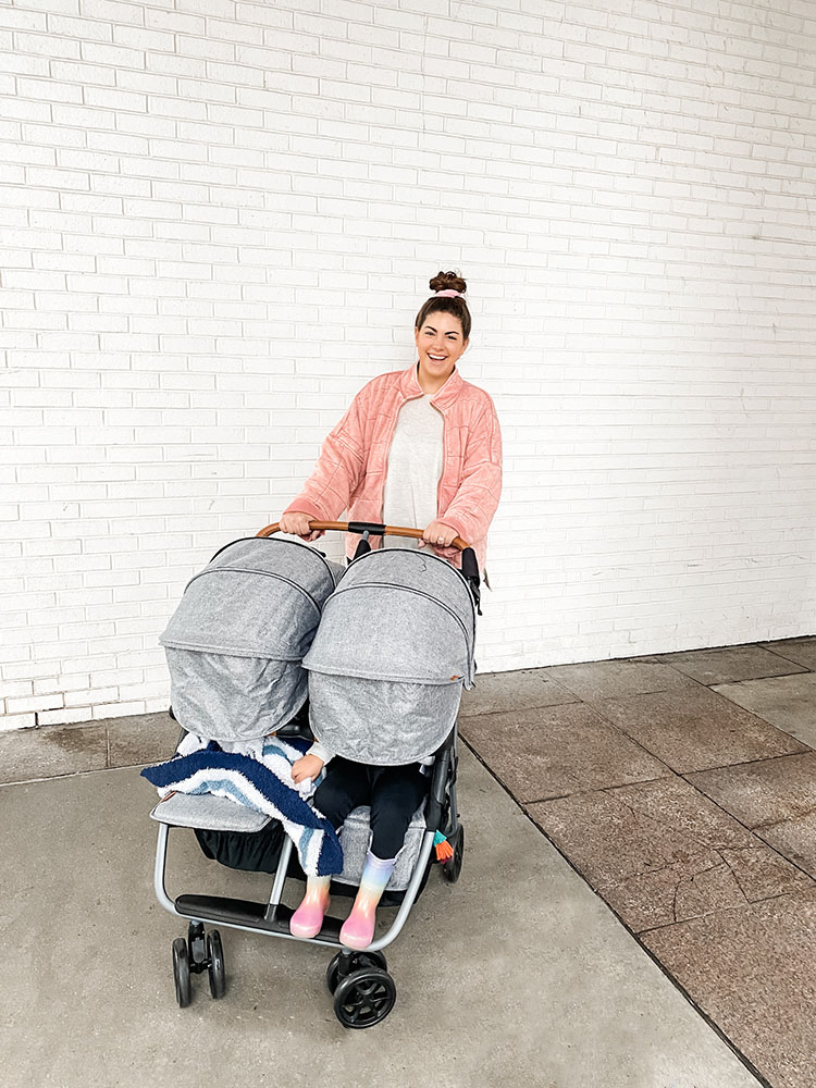 Mom wearing pink jacket and pushing a grey Zoe Twin+ double stroller in Chicago, IL.