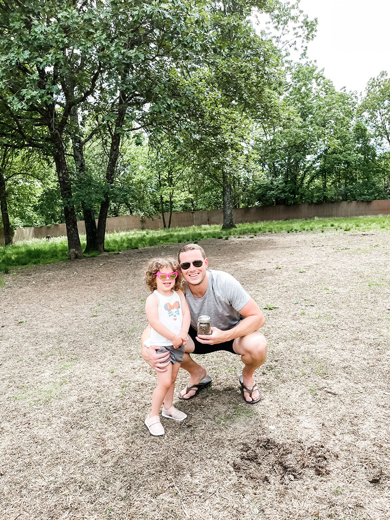 Dad and daughter standing on piece of property with a jar full of dirt.