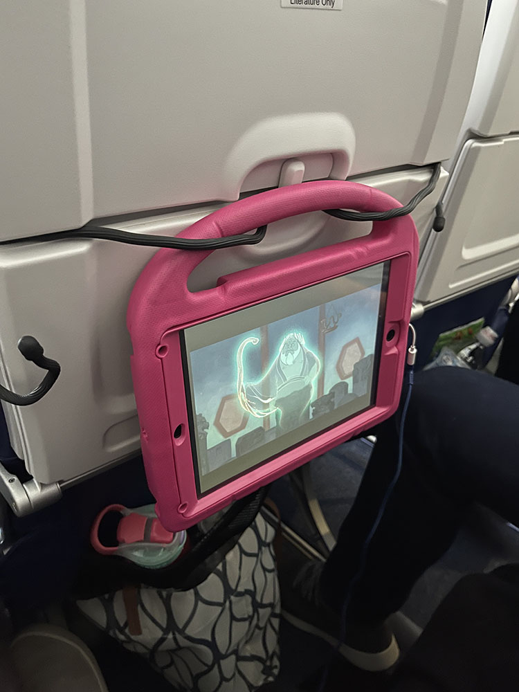 Using gear ties to hold toddler's iPad on the seat back of an airplane.