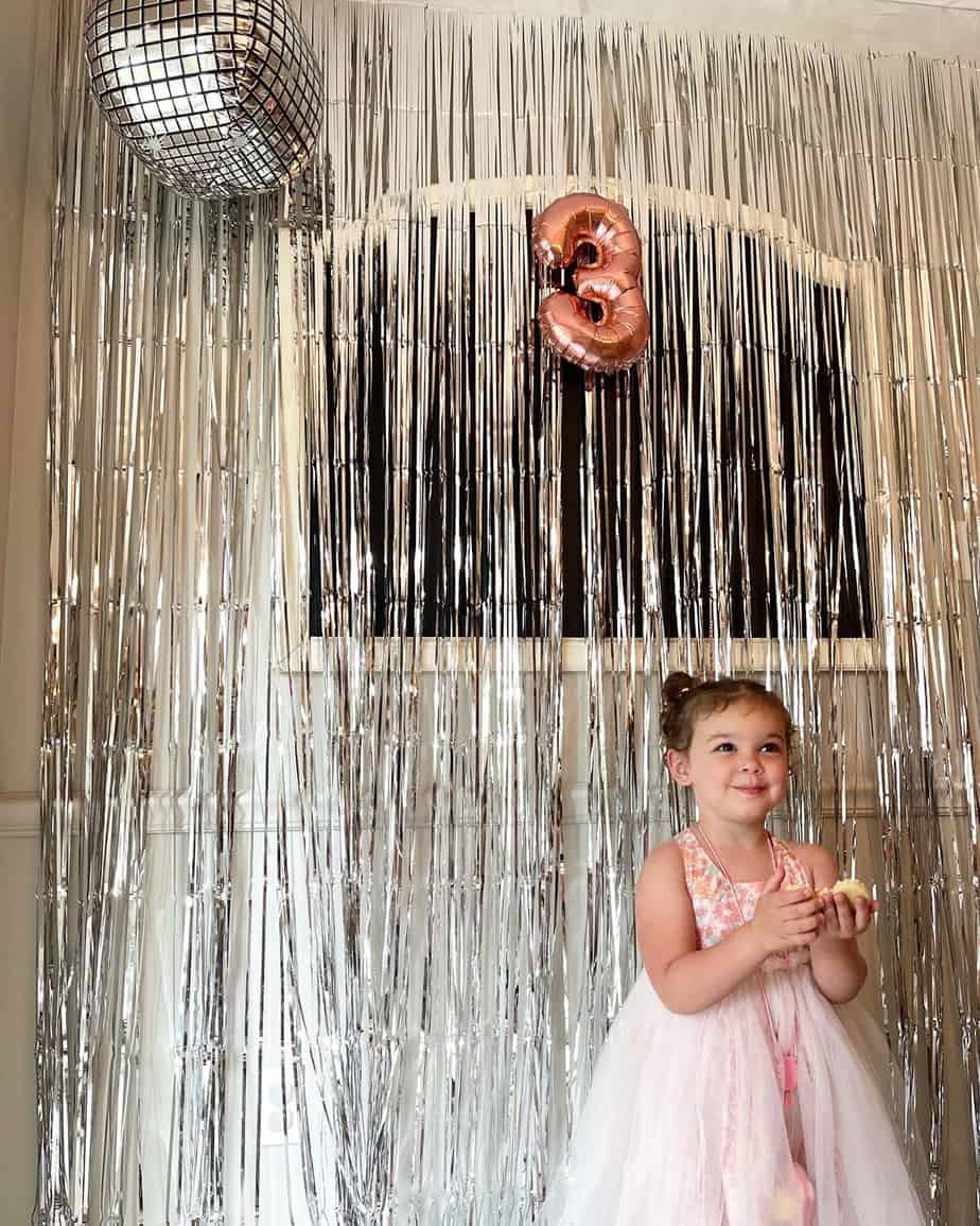 Metallic fringe photo backdrop with disco ball balloon and rose gold #3 balloon hanging.