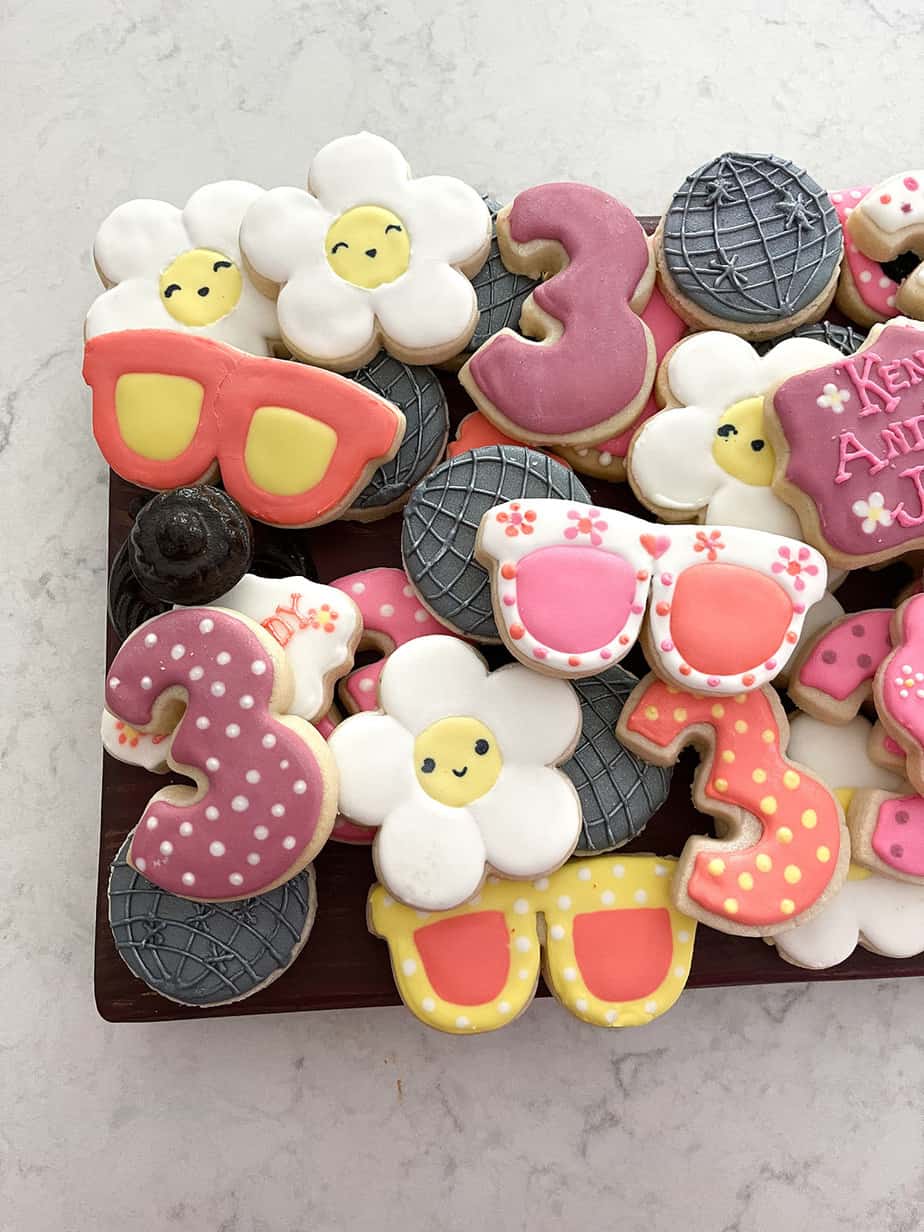 Custom cookies for 70s themed birthday party looking like disco balls, sunglasses and daisies in pink, orange, yellow, silver and white.