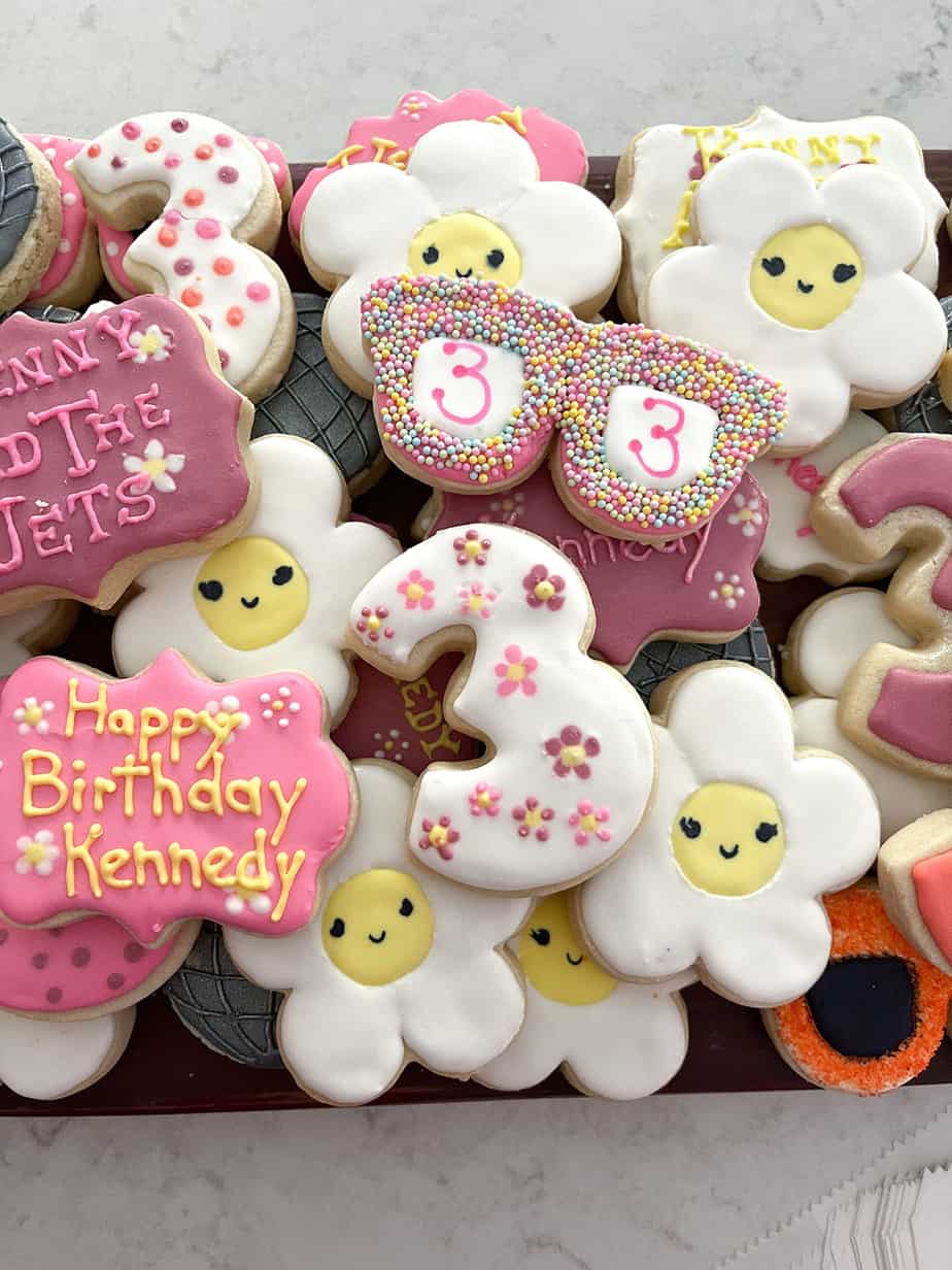 Custom cookies for 70s themed birthday party looking like disco balls, sunglasses and daisies in pink, orange, yellow, silver and white.
