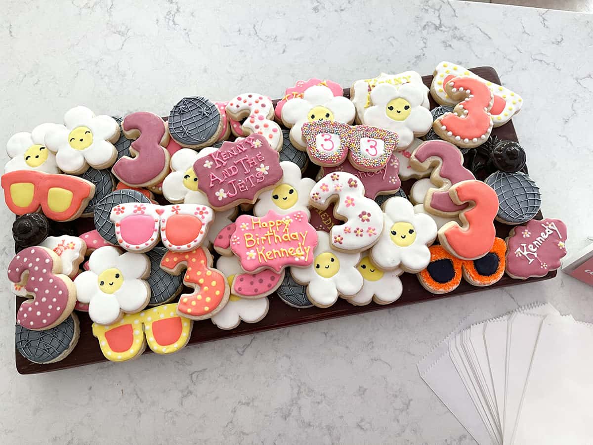 Custom cookies for 70s themed birthday party looking like disco balls, sunglasses and daisies in pink, orange, yellow, silver and white.