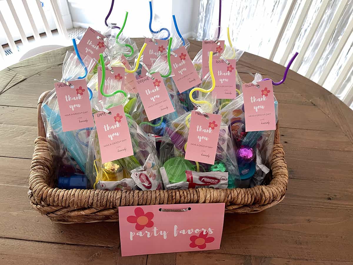 Party favor bags inside of basket with pink tags on them saying "thank you".