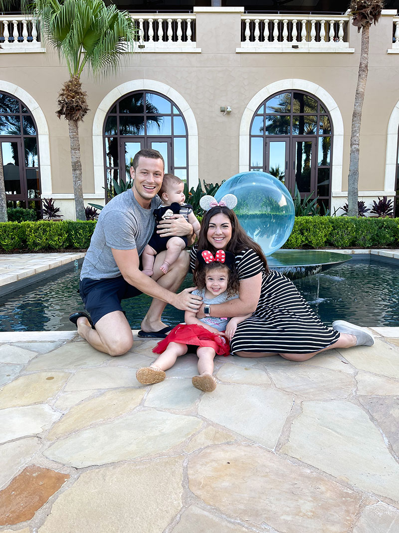 Family of four posing in front of fountain while wearing Minnie Ears.