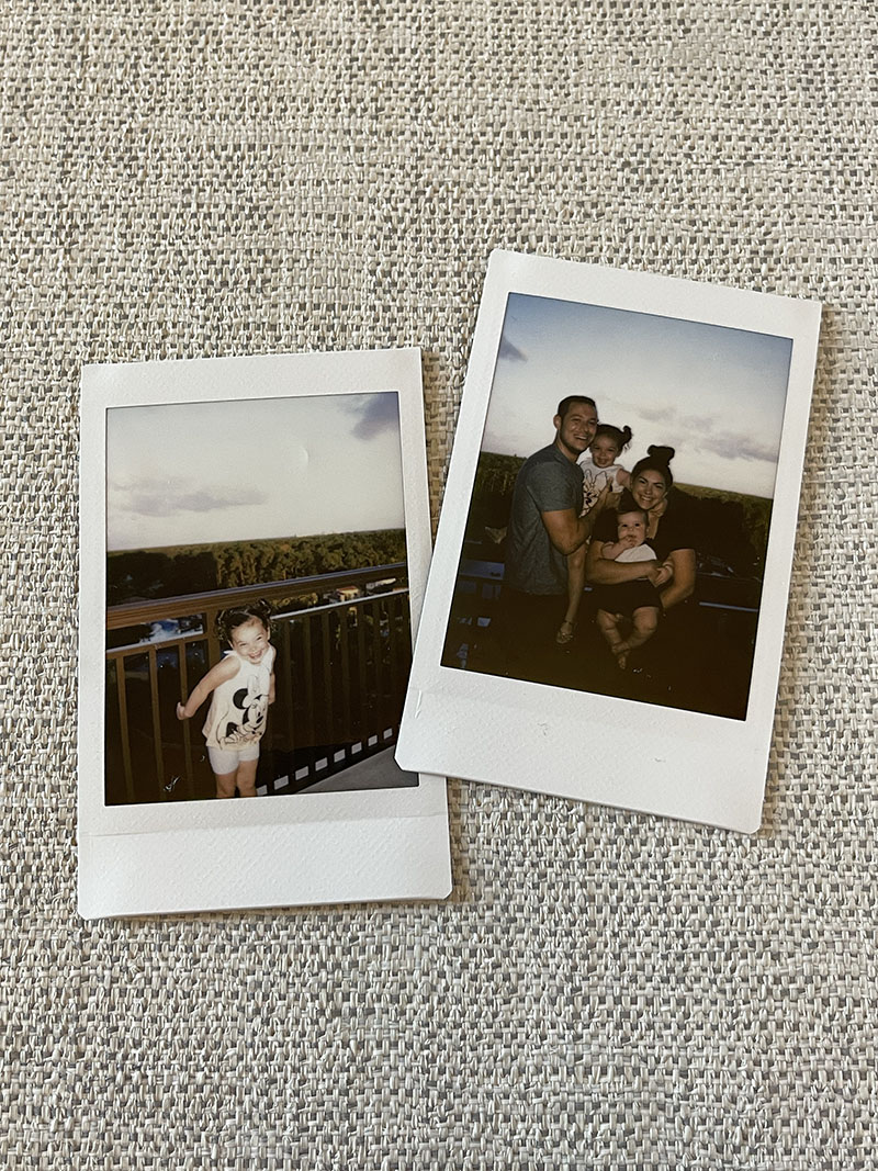 Two polaroid pictures laying on couch ottoman of family at Disney World.