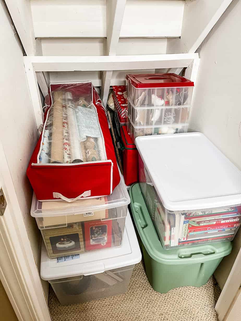 Christmas decor put away in clear plastic bins, wrapping paper organizer, and ornament organizer.