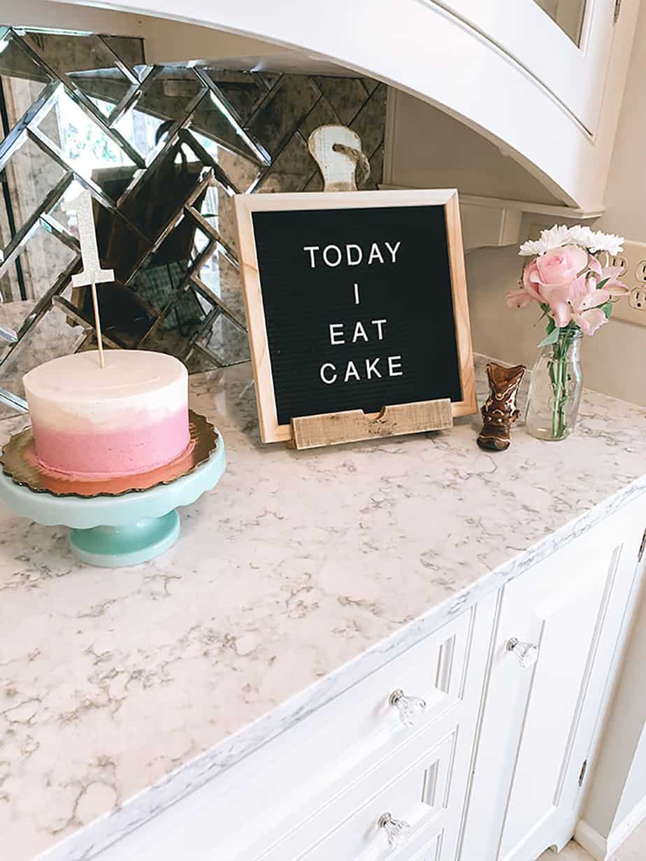 Letterboard saying "today I eat cake" next to small pink and white smash cake with #1 topper in it.