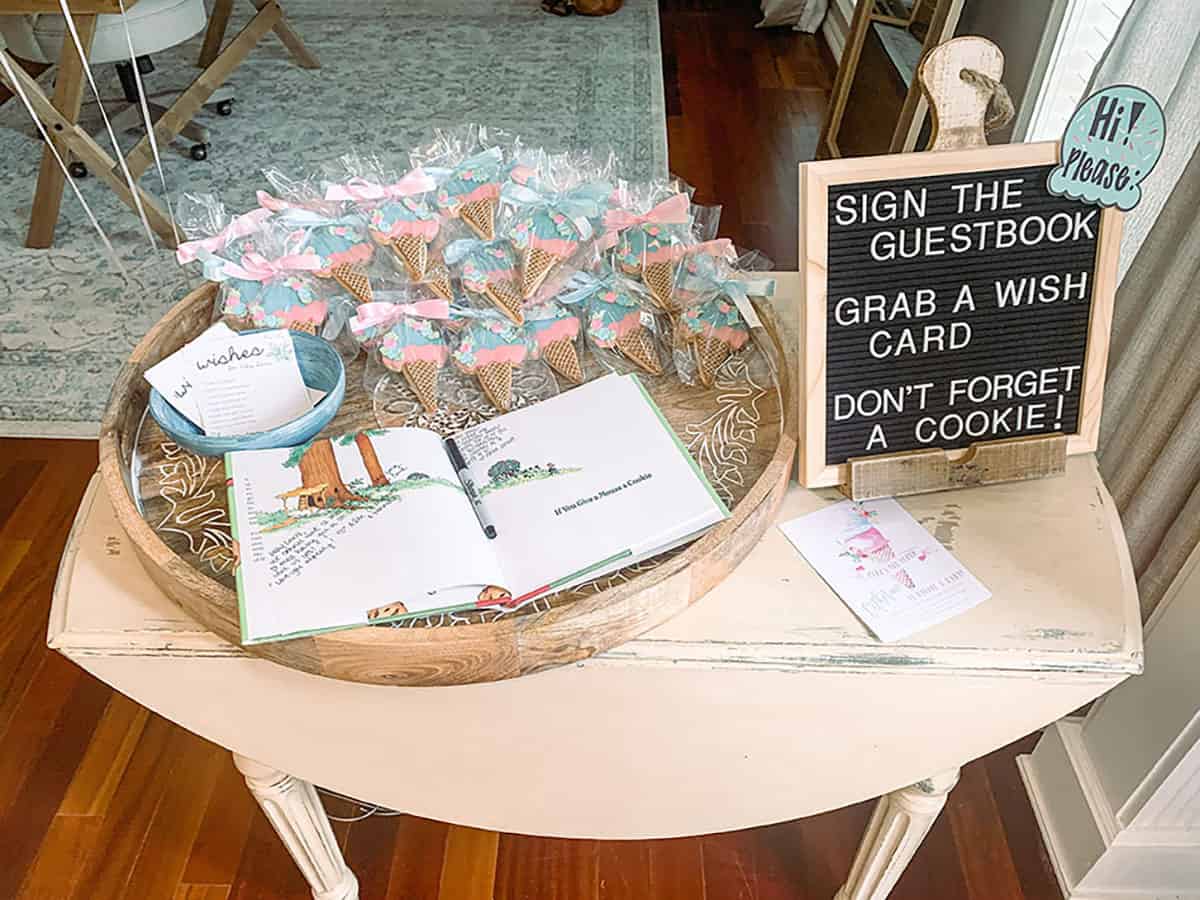 Cookies that look like ice cream cones bagged individually for baby shower guests to take home as a party favor next to guest book to sign.