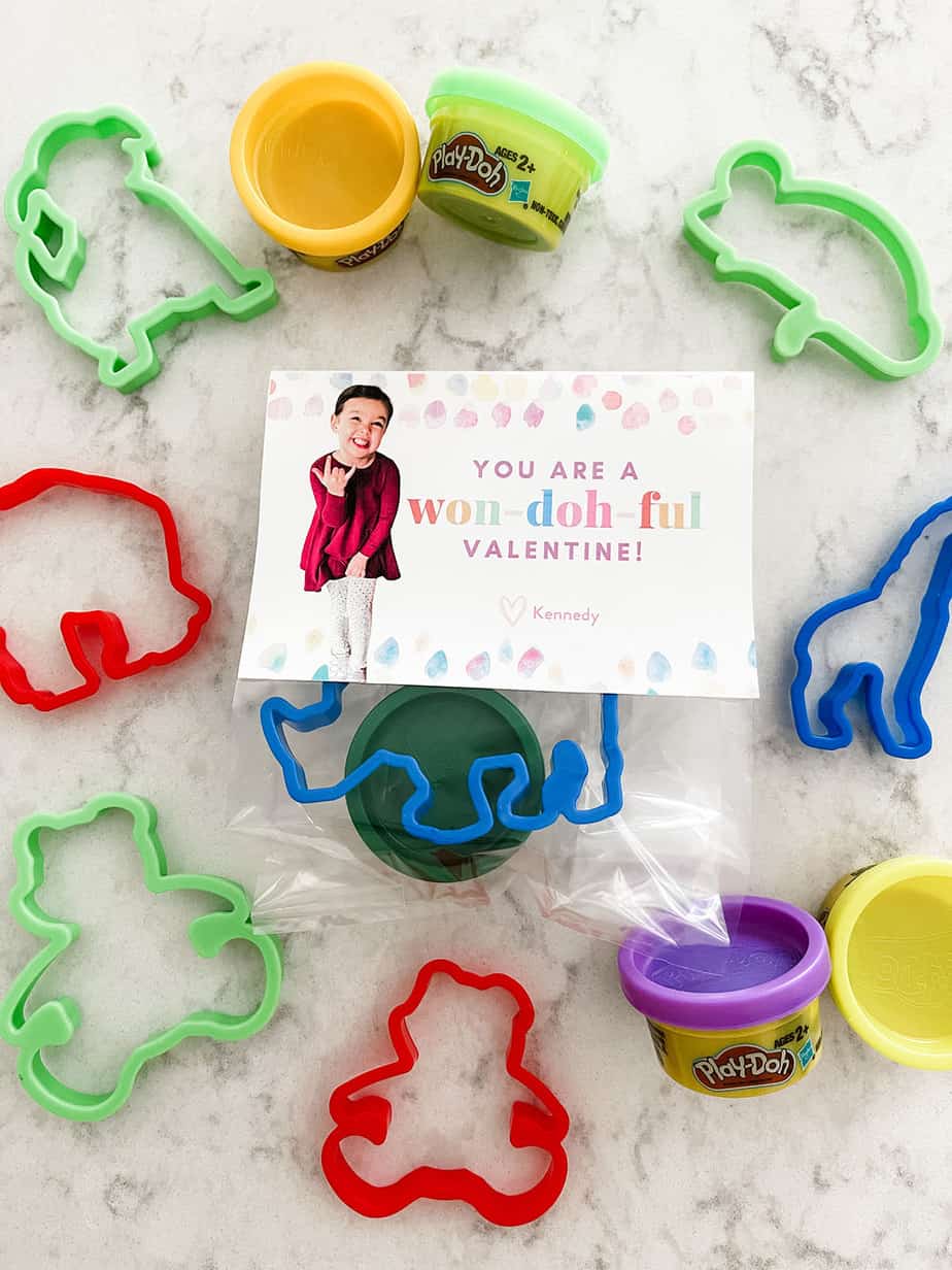 "you are a won-doh-ful valentine" custom valentine printed on cardstock and folded over clear bag filled with mini tub of playdoh and colorful animal shaped cookie cutter.