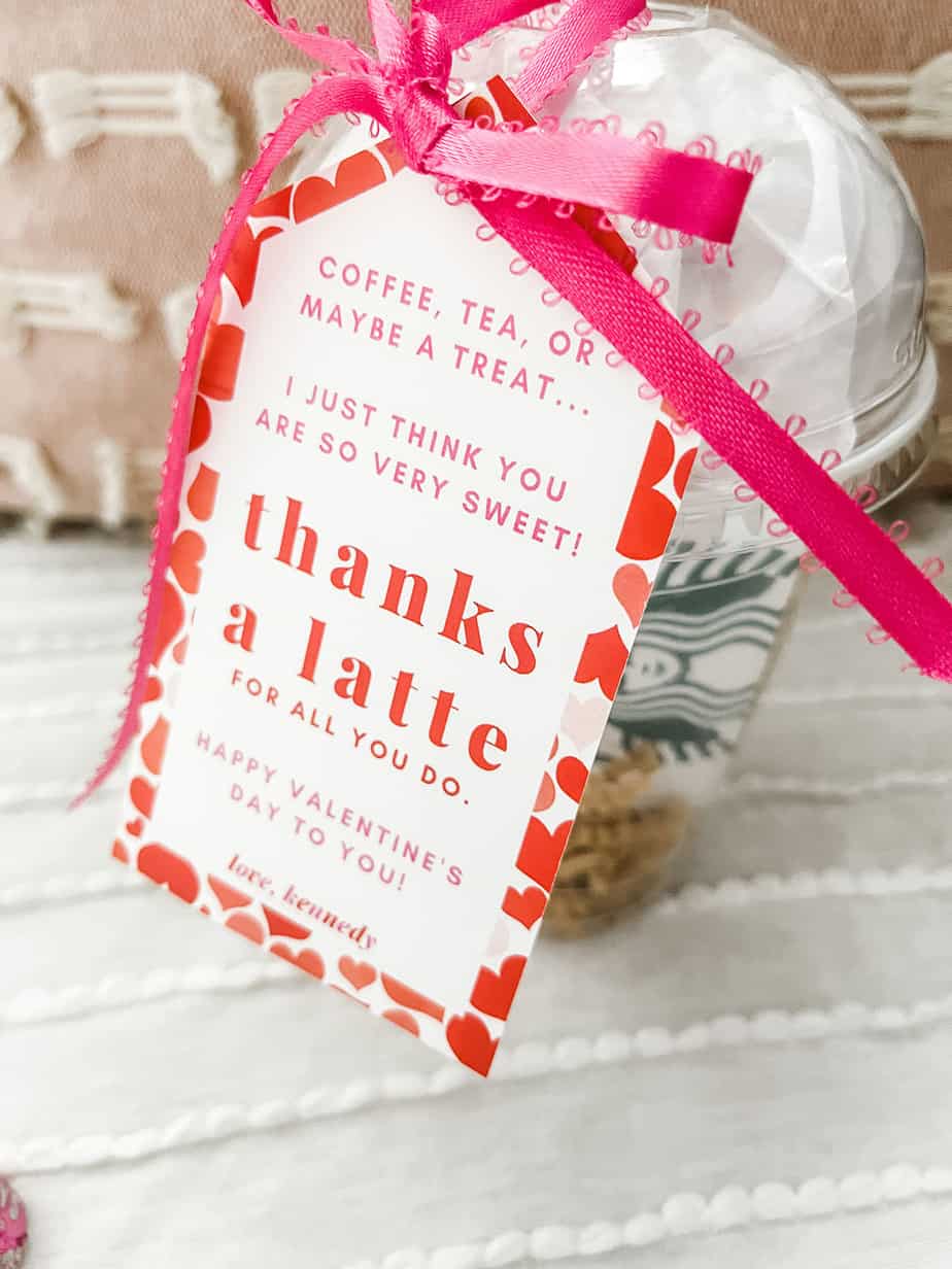 Clear coffee cup filled with chocolates and a gift card with tag tied on saying "thanks a latte" with bright pink ribbon.