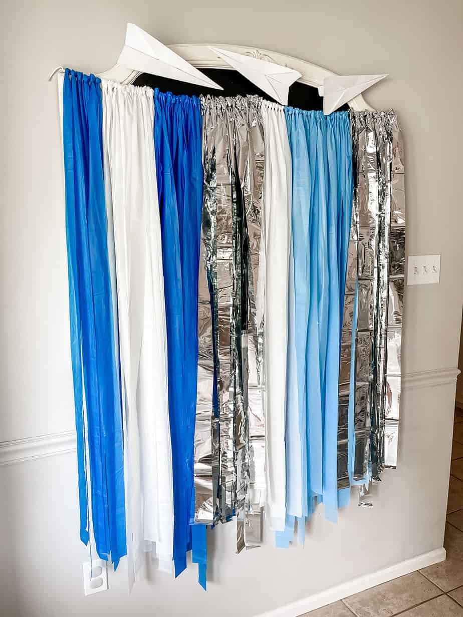 Blue, white and silver metallic backdrop made from plastic tablecloths for first birthday