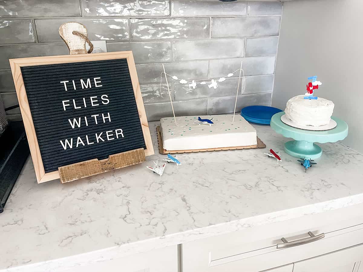 "Time Flies with Walker" sign next to sheet cake and smash cake for first birthday