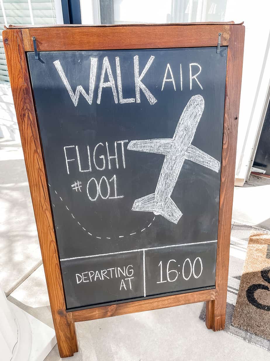 Chalkboard reading "Walk Air Flight #001" on front porch