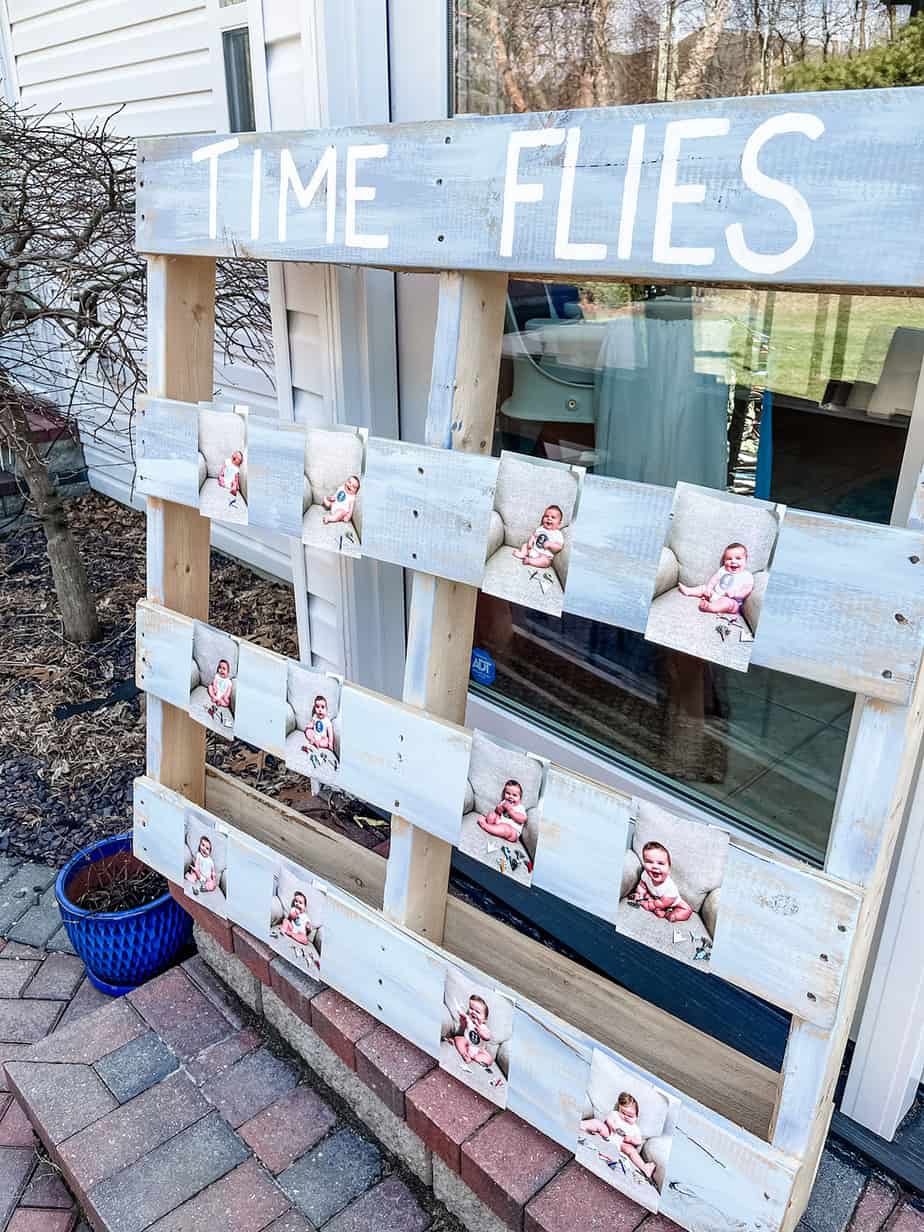 Wooden pallet that reads "time flies" with monthly photos of baby's first year glued to it