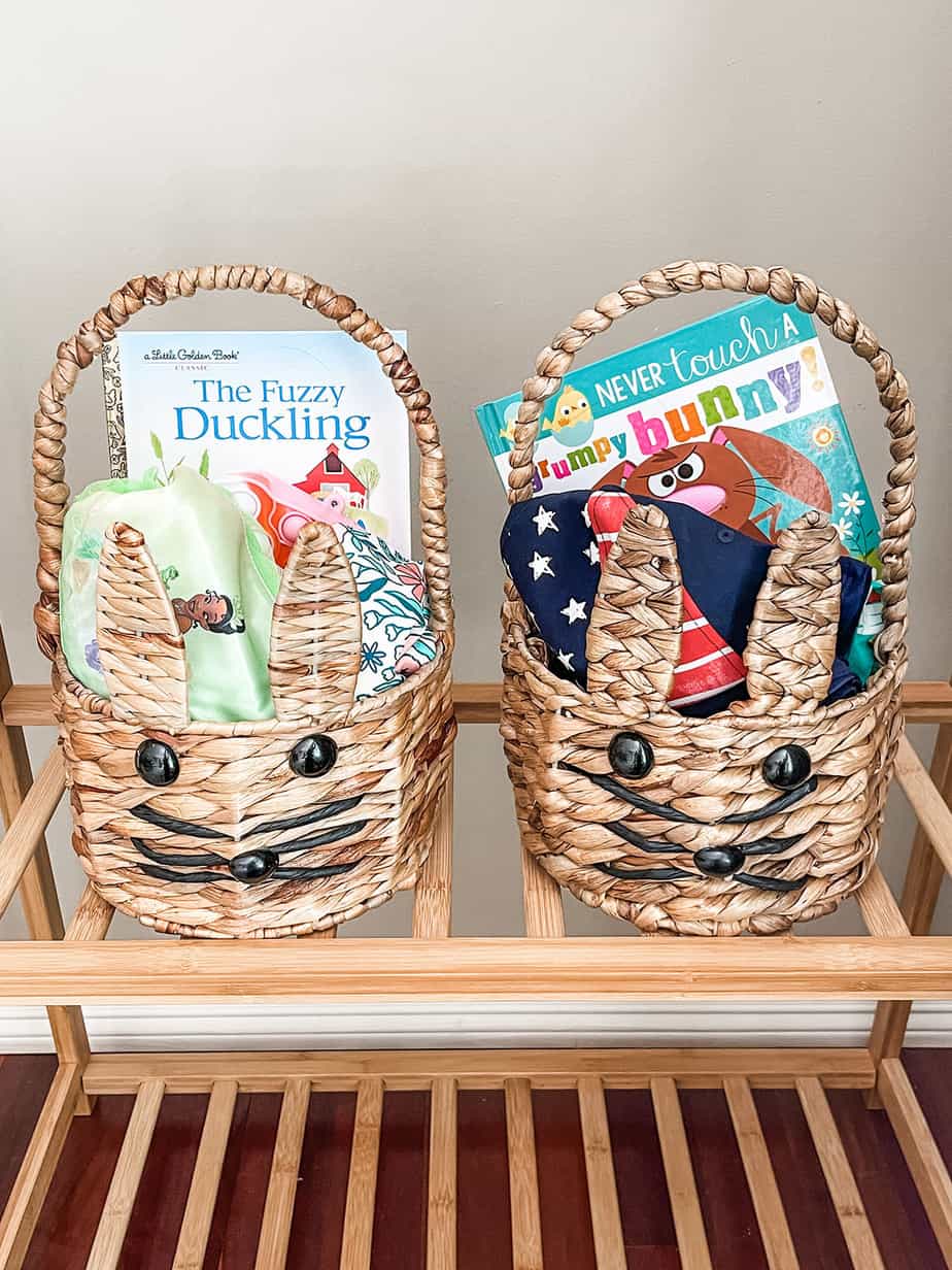 Two bunny easter baskets filled with goodies for children like swimsuits, pajamas, new books and candy.