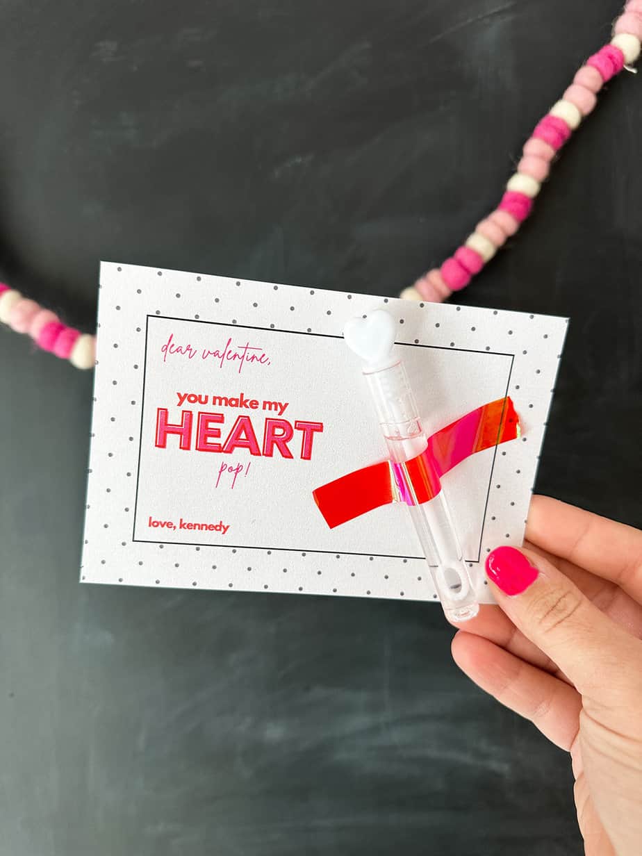 white card with saying "you make my heart pop" and mini bubble wand taped on with pink shiny tape for a class valentine.