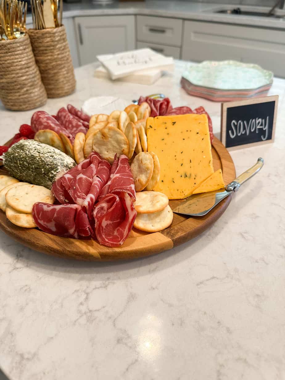 Charcuterie set up on a small round tray with cheese, crackers, meats, fruit.