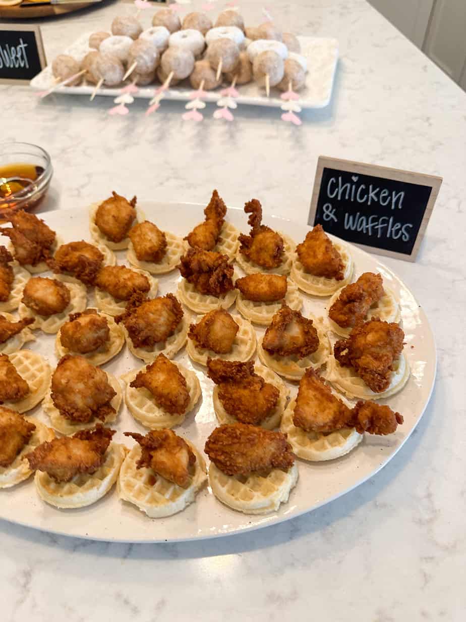 Mini chicken and waffles laying on a large platter made with mini waffles and Chick-Fil-A nuggets for a baby shower.