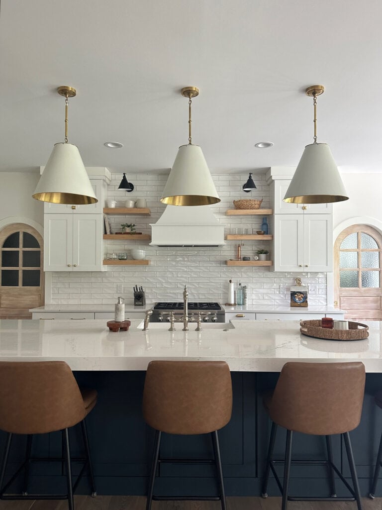 transitional style white kitchen cabinets and blue island with mixed metals of gold, black, and nickel throughout