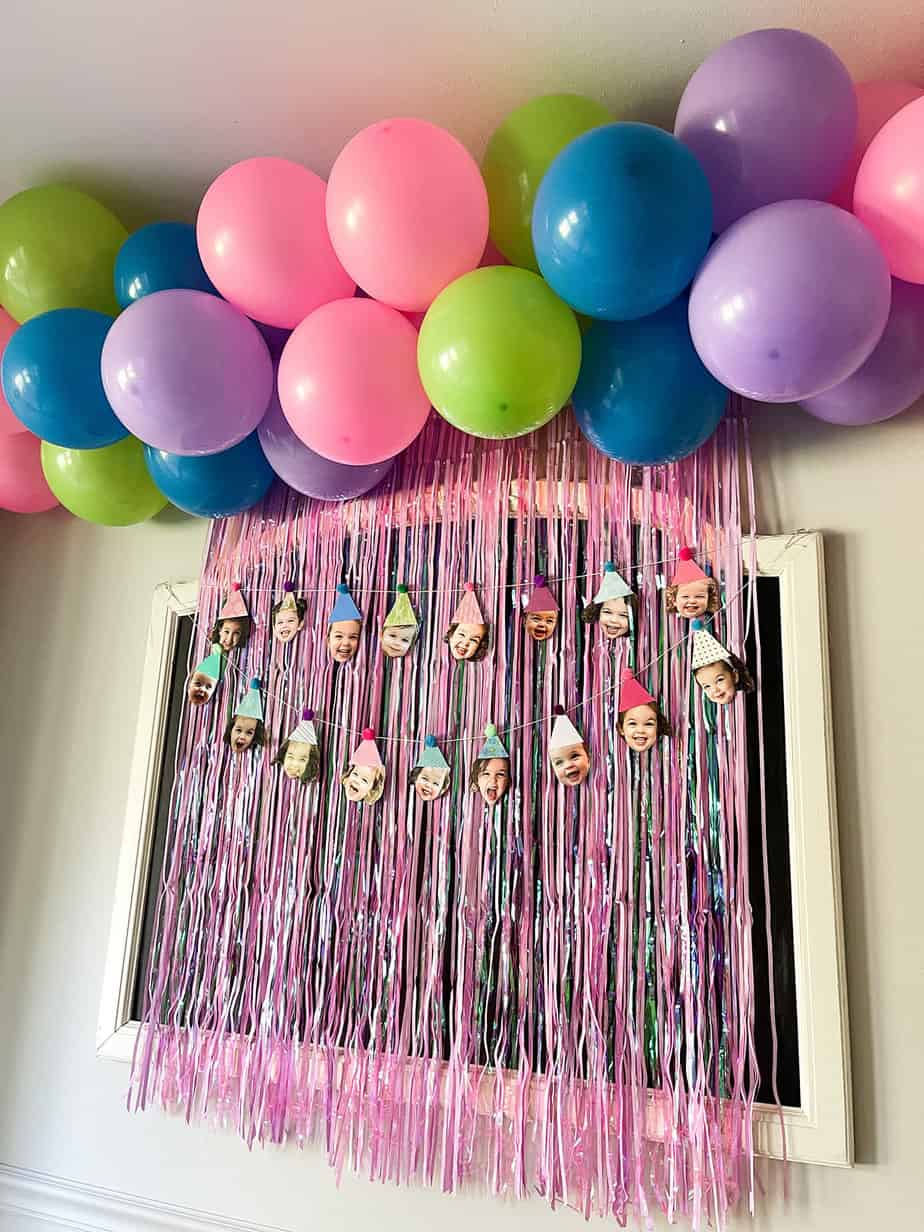 diy balloon garland with hot pink, purple, bright blue, and lime green balloons on top of a hot pink fringe photo back drop 