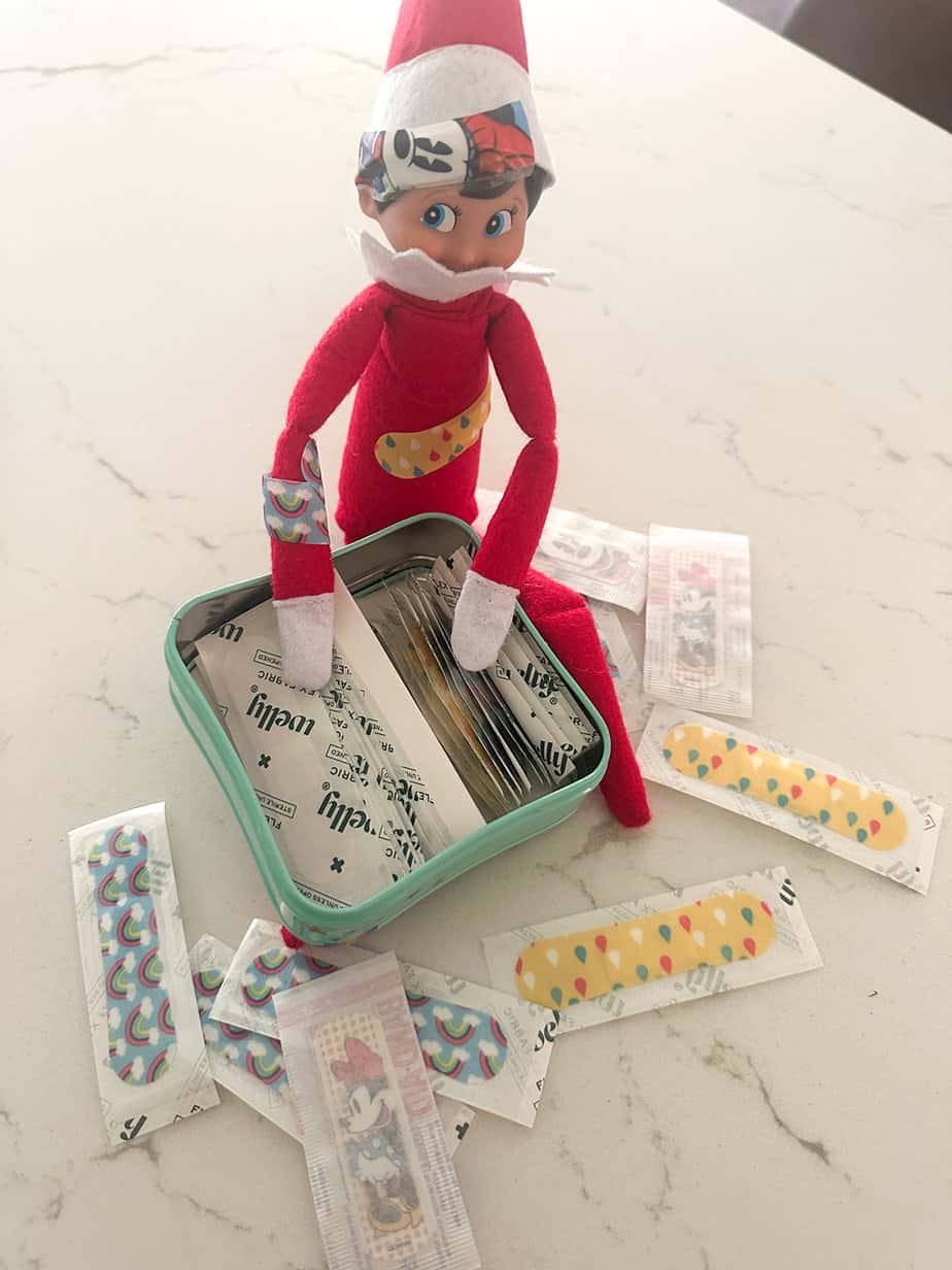 elf on the shelf all covered and playing in the bandaid stash