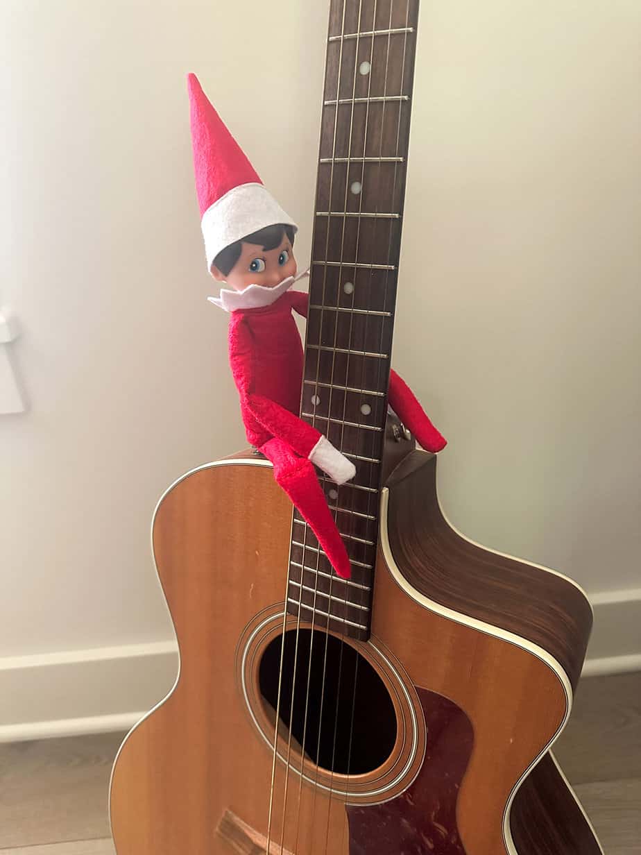 elf on the shelf sitting on a guitar