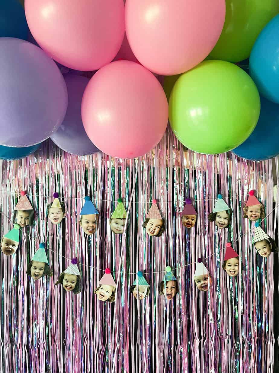 diy balloon garland with hot pink, purple, bright blue, and lime green balloons on top of a hot pink fringe photo back drop