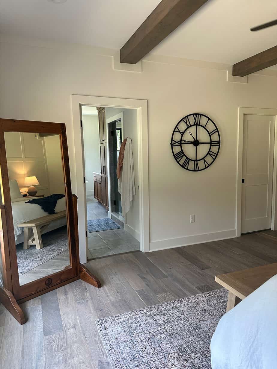 neutral master bedroom with accent wall, white bedding, natural wood details and roman shades