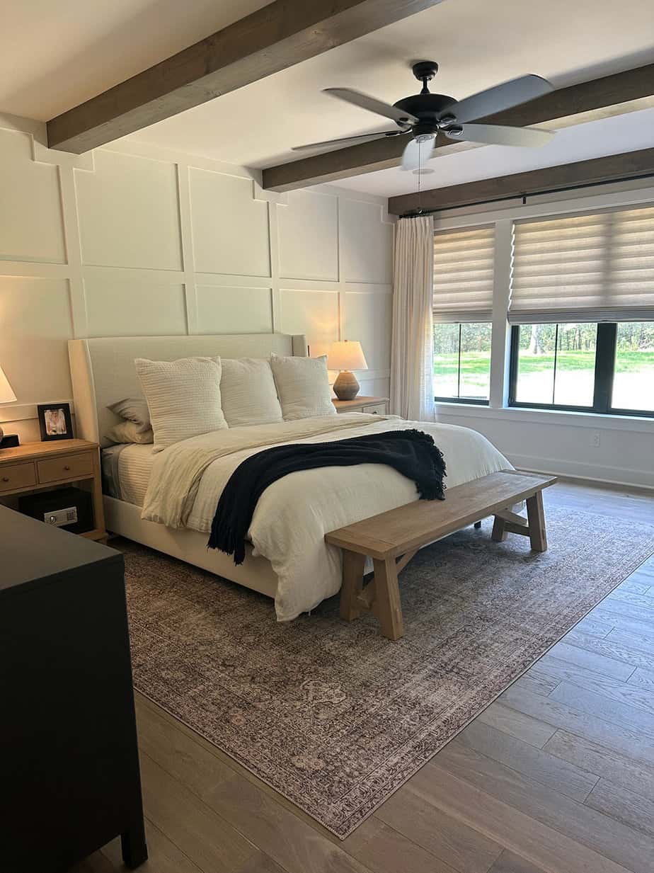 neutral master bedroom with accent wall, white bedding, natural wood details and roman shades