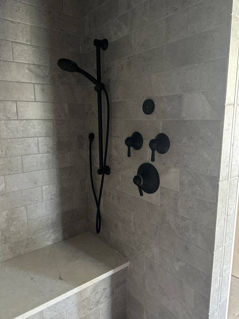 master walk in shower in gray tile and his and hers shower niches for storage